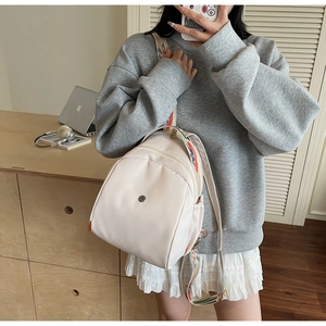 Dettaglio dello zaino in nylon bianco panna con spallacci ricamati etnici e zip in metallo