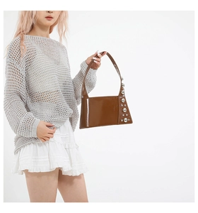 Detail of a brown patent leather shoulder bag featuring silver metallic stud decorations