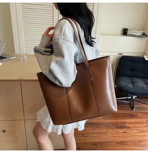 Gedetailleerde weergave van bruine leren shopper met verticale stiksels op houten bureau