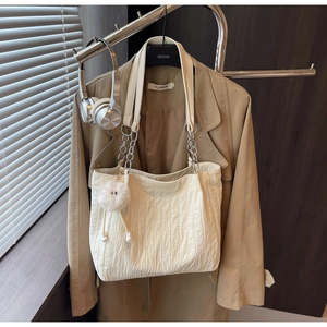 Dettaglio della borsa tote in tela crema con catena argento e ciondolo di peluche