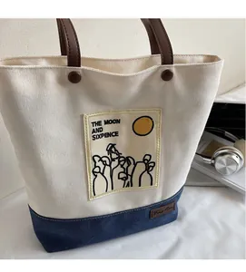 Detail of canvas tote bag featuring contrast patchwork denim and leather handles