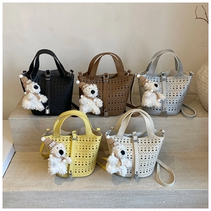 Détail de sacs seaux en cuir ajouré en cinq couleurs avec des breloques ours
