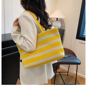 Bolso tote tejido de gran capacidad con rayas amarillas y blancas en una modelo