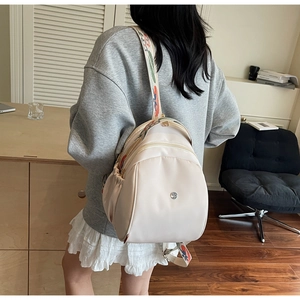 Dettaglio zaino in nylon crema con spallacci ricamati e tasche laterali elastiche