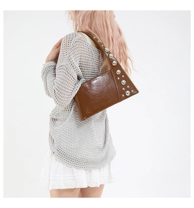 Detail view of brown glossy leather shoulder bag with silver studs and vintage punk style