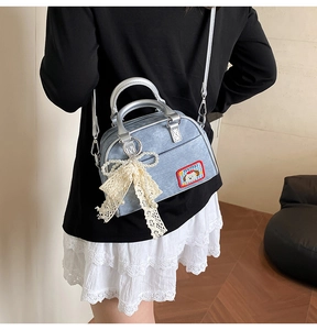 Détail du mini sac en denim bleu clair avec nœud en dentelle et pendentif perle
