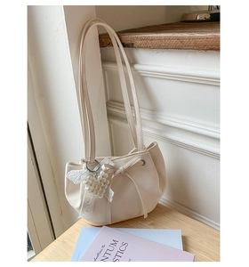 Detail of cream white pleated underarm bag with pearl heart charm and lace bow decor