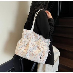 Detailed close-up of a floral canvas tote bag with side drawstring and logo patch