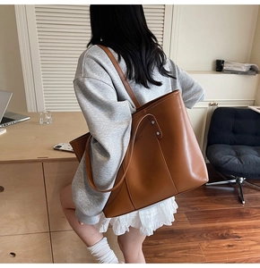 Detailopname van een bruine leren shopper met verticale stiksels en metalen klinknagels