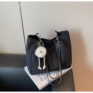 Dettaglio della borsa tote in nylon pieghettato nero con catena argento e ciondolo peluche