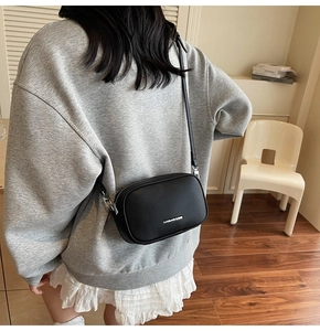 Vue arrière d'un mannequin portant un sac bandoulière noir en cuir à motif litchi