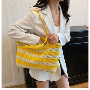 Detalle del bolso tote tejido a rayas amarillas y blancas con textura de malla hueca