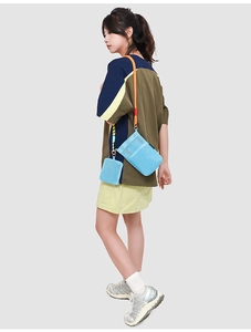 Detail view of light blue mesh crossbody bag with orange woven rope strap and coin purse