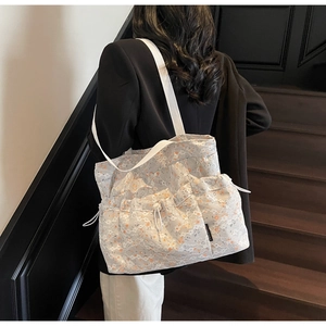 Detailed view of white lace tote bag with floral patterns and drawstring side pockets