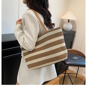 Detalle de bolso tote tejido con rayas marrones y blancas y asas de cuero