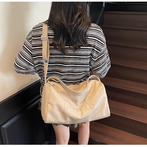 Detailed view of beige tote bag with embossed lettering and adjustable shoulder strap