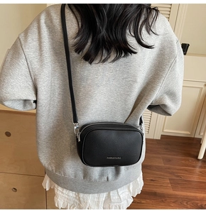 Détail du sac bandoulière en cuir grainé noir avec boucles métalliques argentées