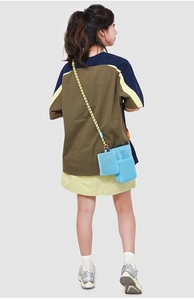 Rear view of model wearing blue mesh crossbody bag with colorful woven rope strap
