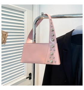 Pink underarm bag with silver rivets hanging on a metal hanger with a black blazer
