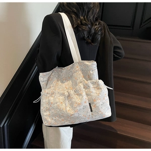 Close-up of lace tote bag featuring floral lining and drawstring side pocket detail