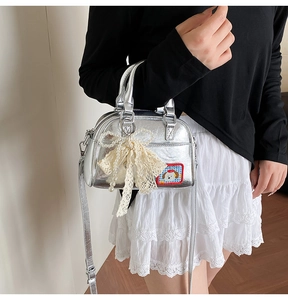 Détail d'un sac à main argenté orné d'un nœud en dentelle, de perles et d'une broderie