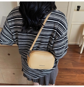 Détail du sac carré en cuir jaune à motif litchi avec ferrures argentées sur modèle