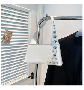 Detail of silver metallic rivet decorations on the smooth white leather shoulder bag