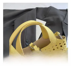 Détail de la poignée large et motif ajouré au laser sur sac en cuir jaune vif