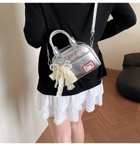 Détail du sac à main argenté métallisé avec patch chien et nœud en dentelle perlée