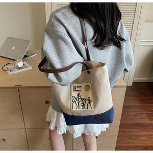 Detail of canvas tote bag featuring literary print and brown leather shoulder straps