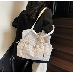 Detail of light blue floral lace tote bag featuring a side drawstring pocket and strap
