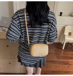 Détail du sac bandoulière en cuir grainé jaune avec sangle réglable et finitions métalliques
