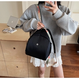 Dettaglio mini zaino nero con tracolla ricamata in stile bohémien e logo in metallo
