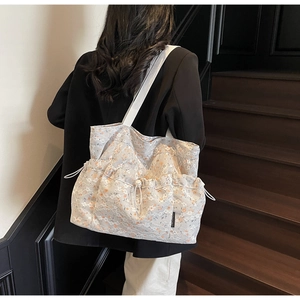 Close-up of floral lace tote bag with drawstring pockets and white woven straps