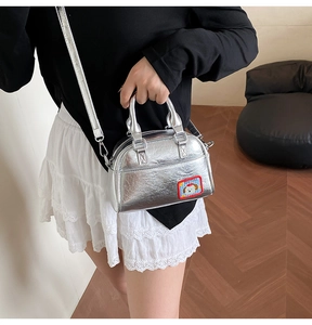 Détail du mini sac bowling argenté avec écusson chien de dessin animé et fermeture éclair
