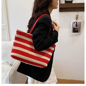 Detalle del bolso tote de punto a rayas rojas y blancas con correa de cuero al hombro