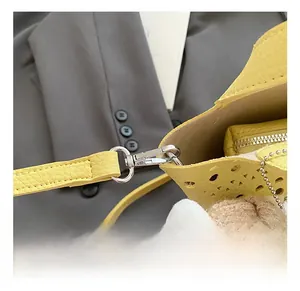 Détail du sac en cuir jaune avec fermoir argenté et motifs ajourés au laser