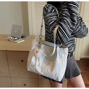 Borsa tote bianca plissettata con tracolla a catena e ciondolo di peluche in ufficio