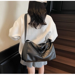 Detailed view of black leather tote bag with Love105°C embossing and textured surface
