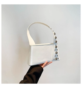 Detailed view of silver rivets on a white leather minimalist underarm handbag