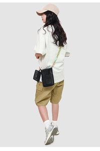 Detail of black mesh crossbody bag featuring textured nylon and woven pattern strap