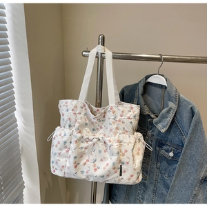 Detail of white floral tote bag with pink and blue flowers and adjustable drawstring pockets