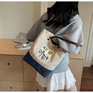 Detail of canvas tote bag with leather strap and moon illustration worn by a model