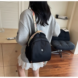 Dettaglio di uno zaino in nylon nero con tracolla etnica ricamata colorata