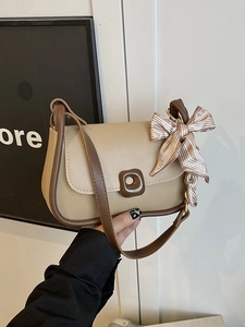 Beige faux leather shoulder bag with brown trim and decorative scarf accessory