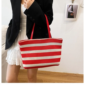 Detalle del bolso tote de punto a rayas rojas y blancas con asas de cuero en modelo