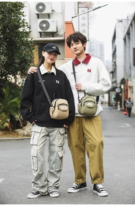 Street style shot of khaki and olive green crossbody bags with wide black straps