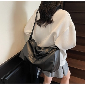 Detail of the love 105 degree embossed text on a large black shoulder bag for women