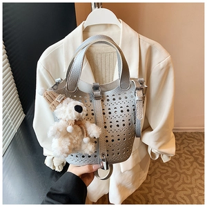Vue détaillée du sac seau argenté ajouré avec motifs au laser et charmant ours en peluche