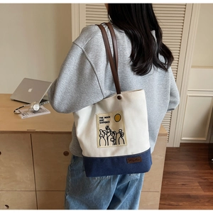 Detail of canvas tote bag with contrast navy base and yellow art patch embroidery